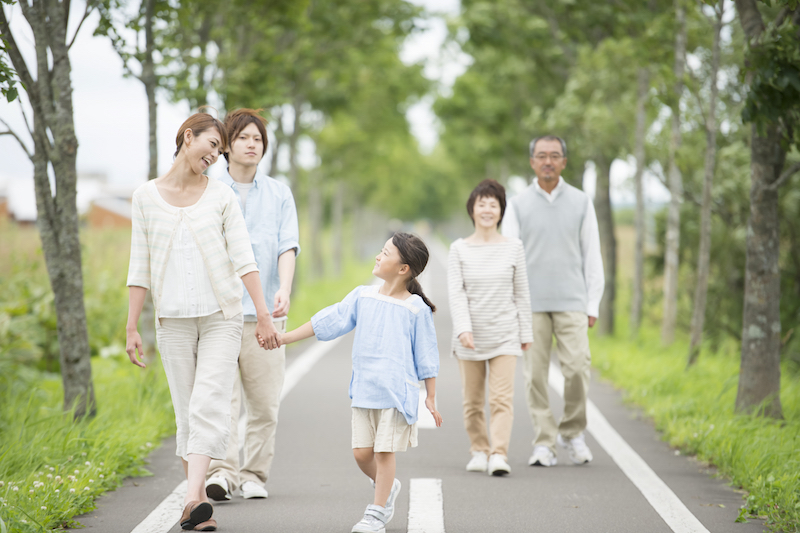 自然の中を孫と子供と歩くシニア夫婦