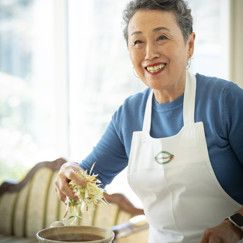 鍋に野菜を入れる女性