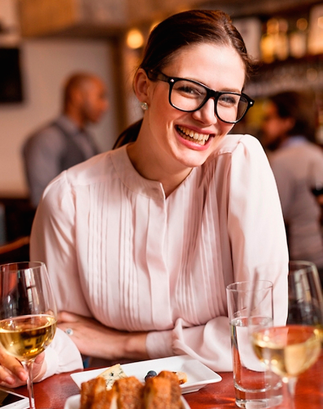 カフェでワインと食事を前に笑顔のメガネを掛けたフランス人女性