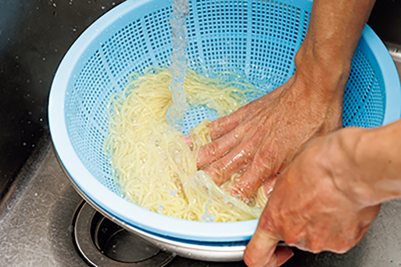 麺を流水で揉み洗いしている