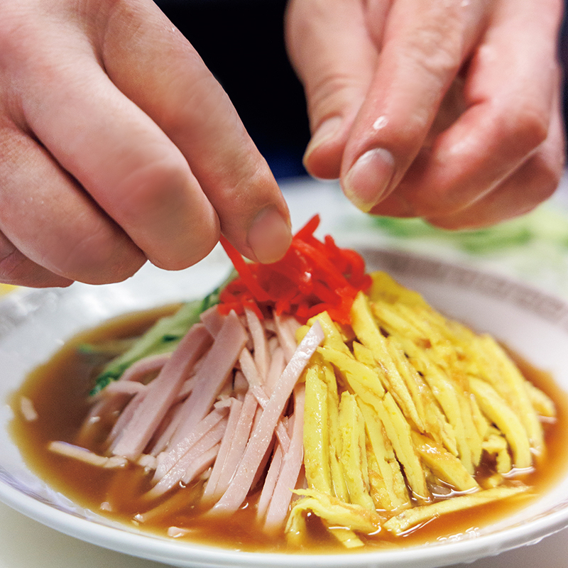 冷やし中華に紅生姜を乗せている