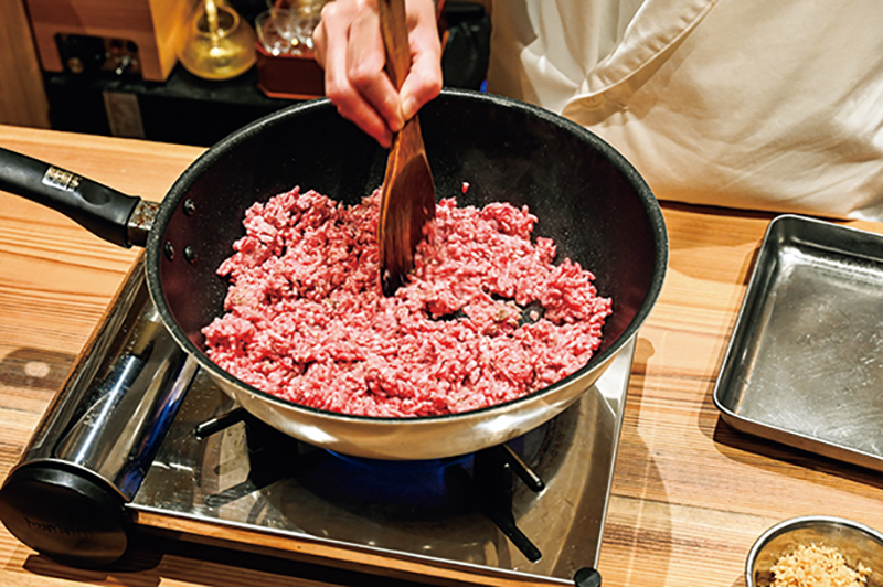 へらで押しつけてひき肉を焼いている