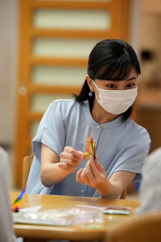 折り鶴を手に入居者と会話をされる佳子さま。（2025年8月、写真／JMPA）