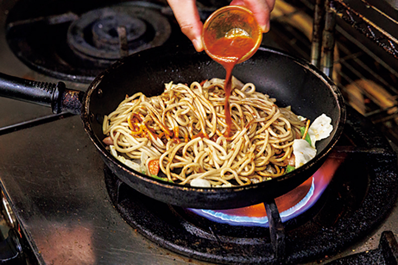 麺にソースをかけている