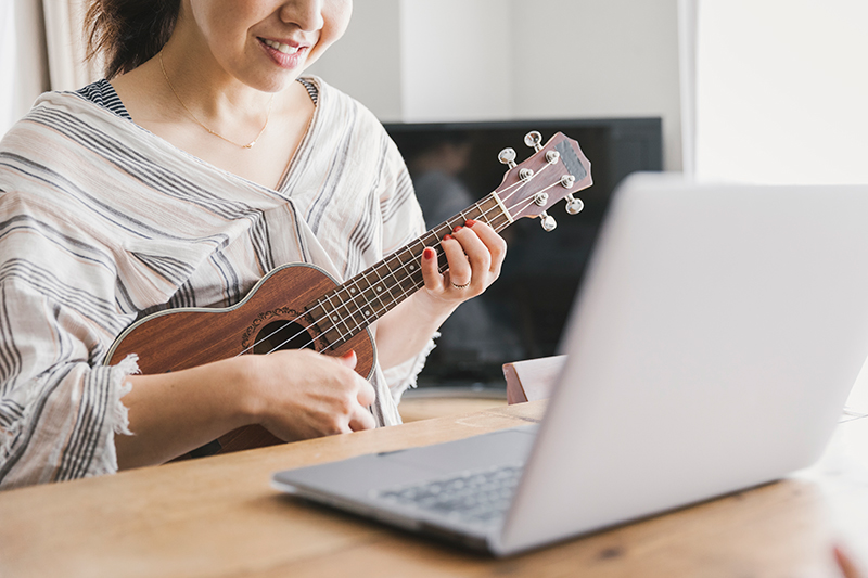 パソコンを見ながら楽器を弾いている