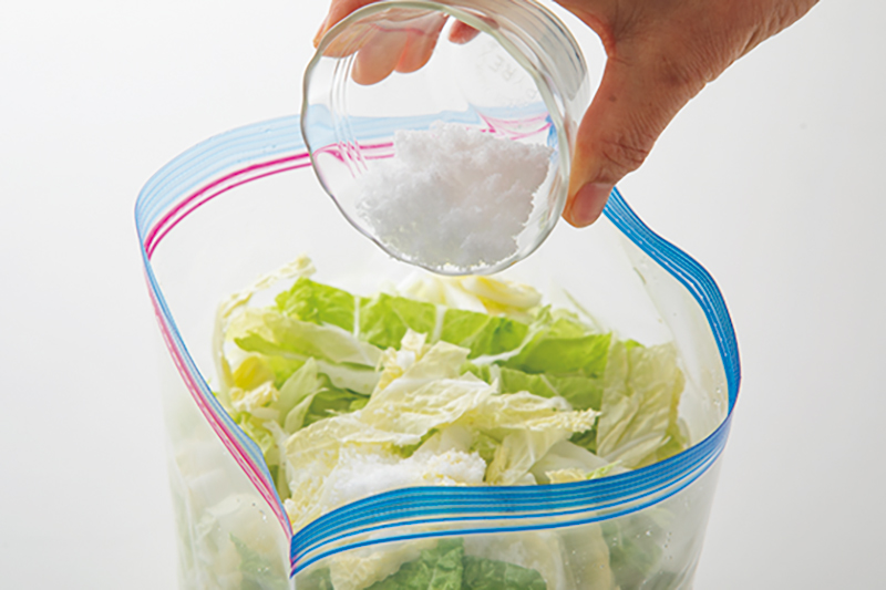 白菜が入ったフリーザーバッグに塩を入れている