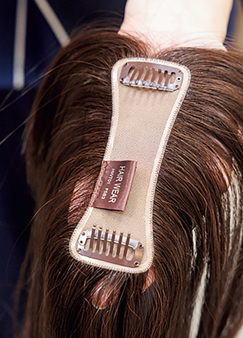 ストッパーを自毛に挟み、パチンと留めるだけで装着できる