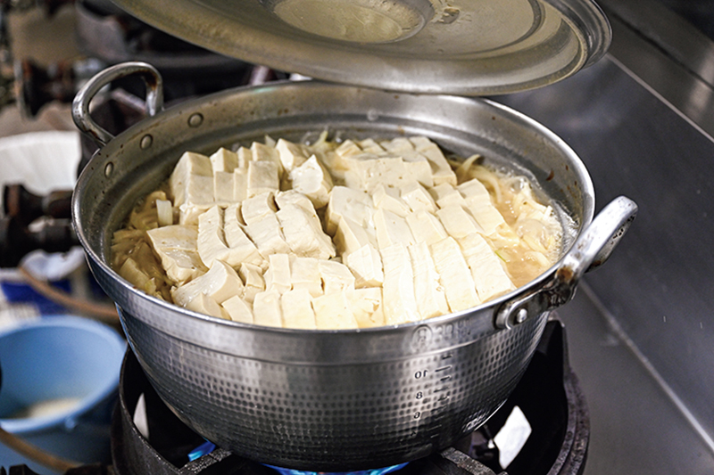 鍋のふたを開けている