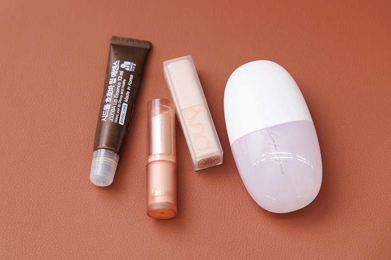 いつも持ち歩くリップ3種とミスト。（写真左から）『シドムル ホホバリップエッセンス』（790円）、『デイジーク ムードグロウリップスティック 03』（1540円）、『ロムアンド ゼロマットリップスティック 09』（1399円）、『コスメデコルテ コンフォート デイミスト セット＆プロテクト』（60ml 3520円）／すべて私物（価格はすべて編集部調べ）