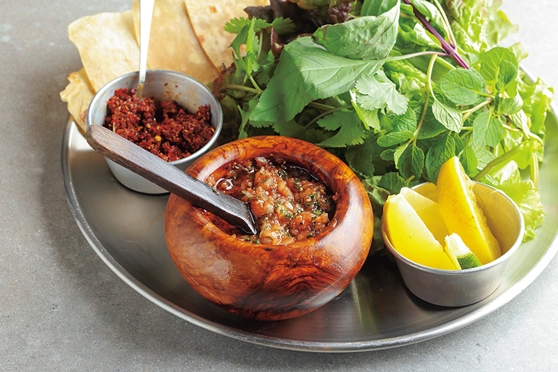 たっぷりのサンチュとハーブ、サルサ風のチミチュリソース、ハリッサ、ロティの盛り合わせは、チャージ代として提供（撮影／菅井淳子）