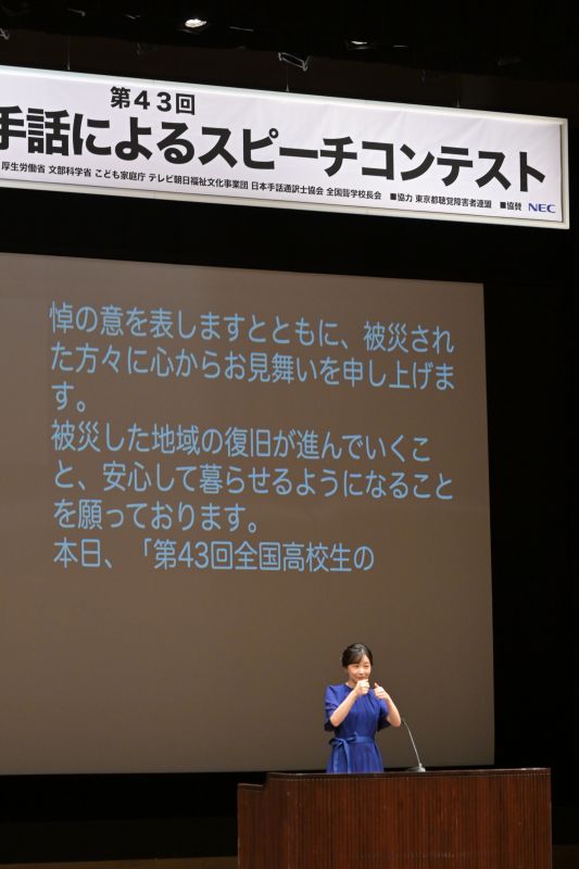 スピーチの最中、背景には文字での説明も。（2026年8月、写真／JMPA）