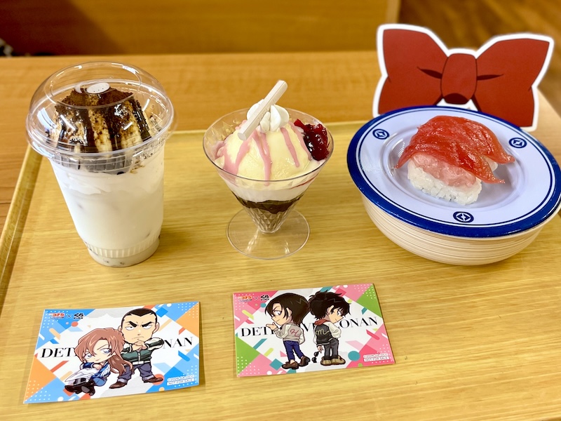 劇場版『名探偵コナン ハイウェイの堕天使』の公開を記念したコラボメニュー。左から、千速と重悟のコーヒーミルクフロート 480円 （ステッカー付）、松田と萩原のチョコ＆ベリーパフェ 480円（ステッカー付）、江戸川コナンのトリックまぐろ 300円（蝶ネクタイ型変声期ピック付）